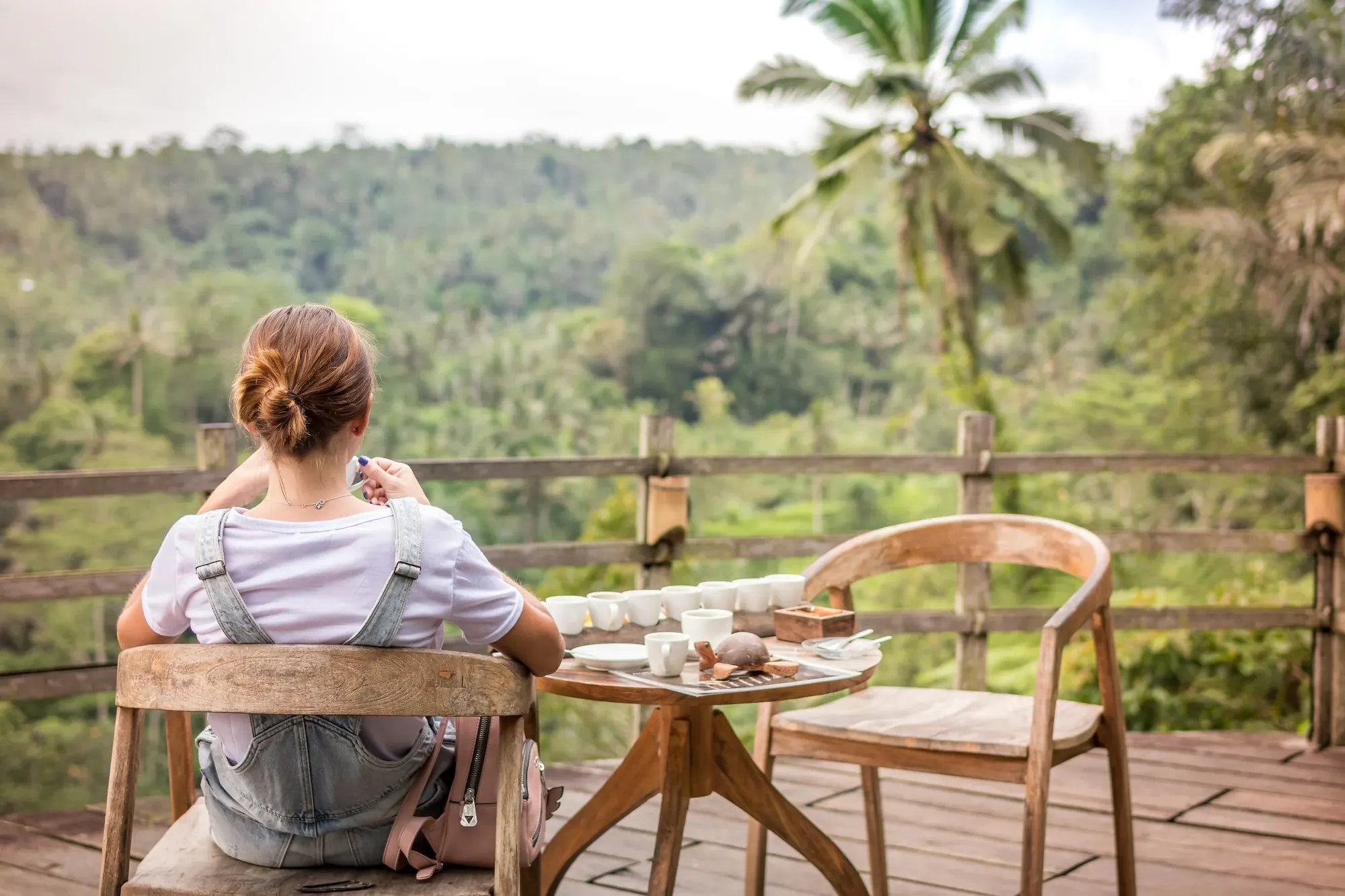 Woman enjoying coffee on a balcony overlooking the trees